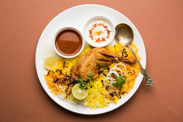 Hyderabadi chicken or dum biryani, served in a Kadhai or bowl with yogurt dip . selective focus