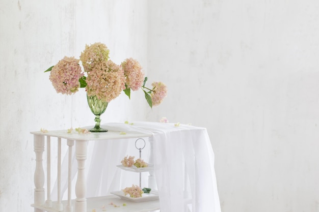 Hydrangea in green glass on white background