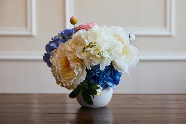 Hydrangea and piones in white vase on wooden table at home