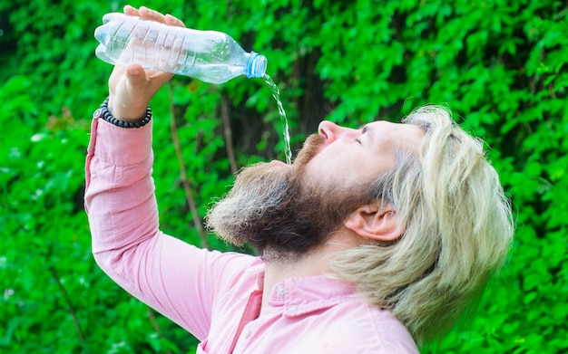 水分補給の概念。水を飲むひげを生やした男。水のボトルを持つ男性。健康的な生活様式。