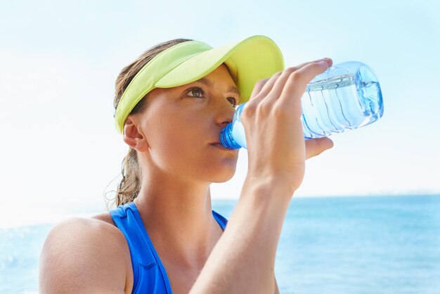 水分補給が鍵です走った後に水を飲む魅力的で運動的な若い女性