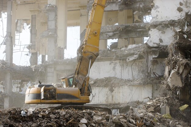 Фото Гидравлический экскаватор-разрушитель во время сноса бетонной пыли в воздухе