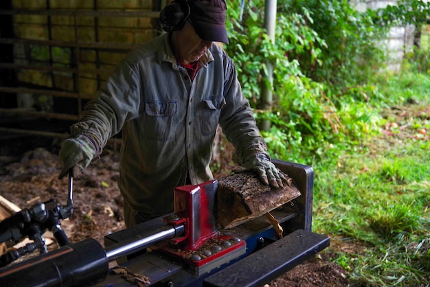 Photo hydraulic log splitter blade cuts into wood with workman