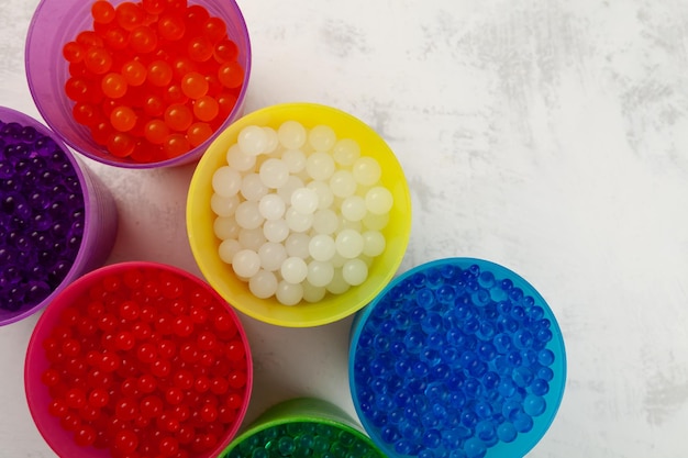 Premium Photo  Hydrogel balls or water beads in plastic cups top view  orbeez toy flexible gel balls for playing