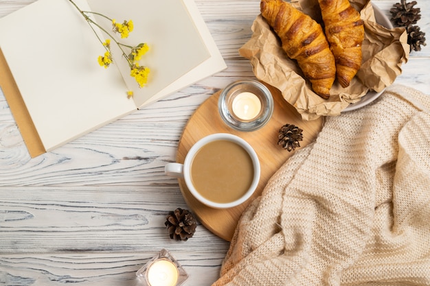 Photo hygge composition with coffee, candles, fresh croissants and knitted plaid. overhead flat lay