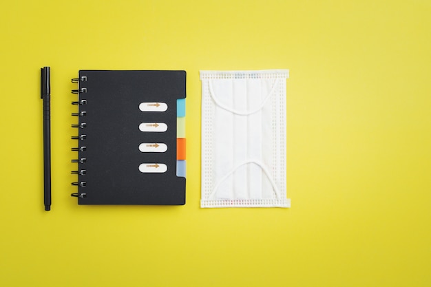 Hygiene face mask with office supply as notebook and a pen