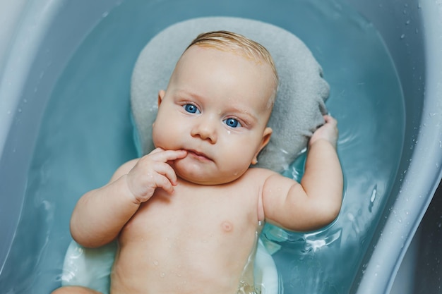 Foto igiene dei neonati e dei bambini il bambino giace su un supporto e fa il bagno in una vasca da bagno fare il bagno di un neonato in un bagno