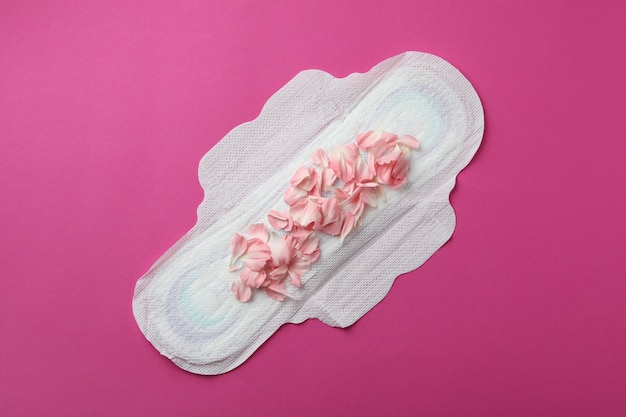 Hygiene pad with petals on pink background