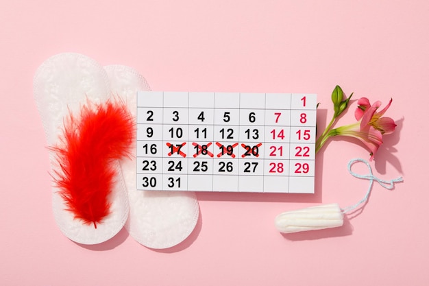 Hygiene products during the lunar cycle with a calendar on a pink background