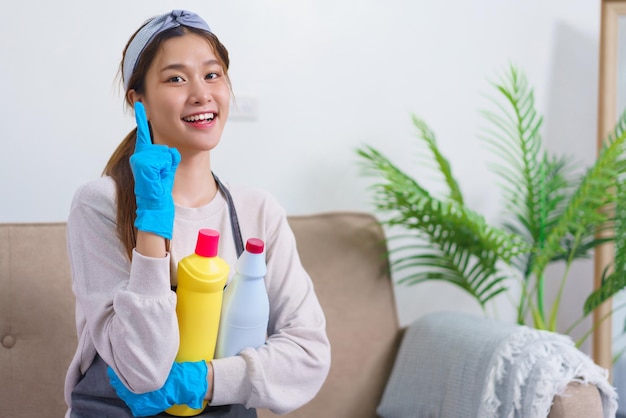 Hygiëne schoonmaakconcept Huishoudster doet duimen omhoog en houdt schoonmaakoplossing vast om huis schoon te maken