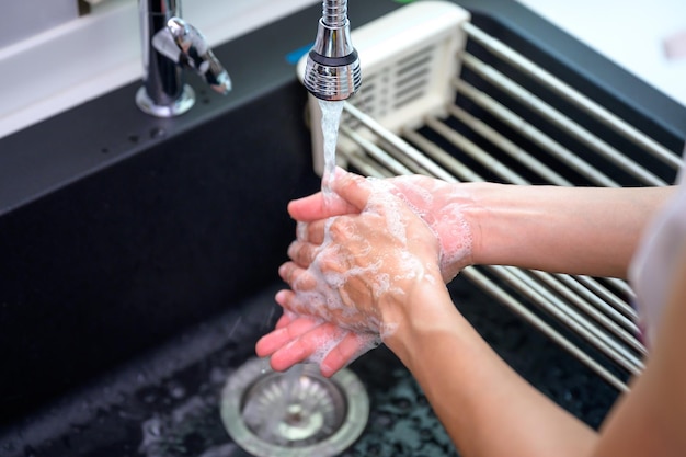 Hygiëne van vrouwen die zeep gebruiken om hun handen onder de kraan te wassen Details van handen wassen in overeenstemming met het concept van hygiëne