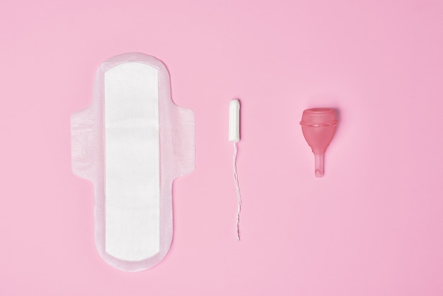 Hygienic feminine tampon for menstruation, menstrual cup, pad on pink background