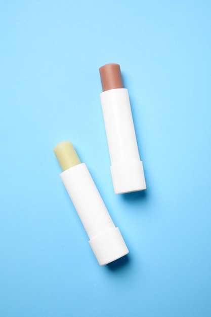 Hygienic lipsticks on light blue background flat lay