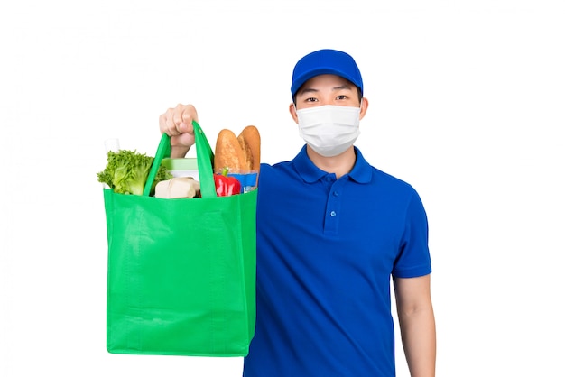 Гигиенический человек, носящий медицинскую маску, держащую сумку для продуктового супермаркета, предлагающую услугу доставки на дом, изолированную в белом