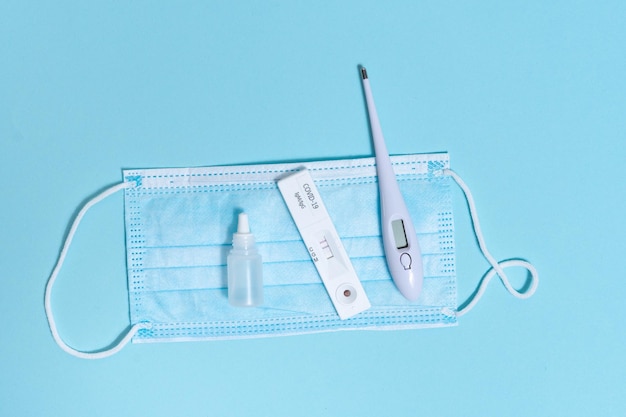 Hygiënische kit voor bescherming tegen Covid19 op een blauwe geïsoleerde achtergrond Wegwerpbare beschermende maskerdesinfecterende thermometer en coronavirustest