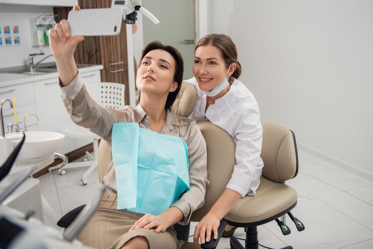 hygiëniste of orthodontist en haar patiënt die selfie maakt met een smartphone na een succesvolle behandeling