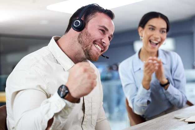 Foto in realtà l'ho fatto. inquadratura di un giovane agente di call center seduto in ufficio che festeggia un successo mentre il suo collega lo sostiene.