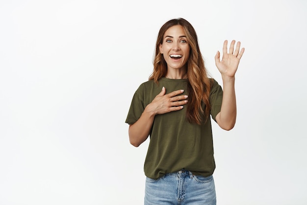 Foto sono allegra donna di mezza età alzare la mano e mettere il braccio sul petto sorridente amichevole dicendo il suo nome presentarsi o fare volontariato vuole partecipare sfondo bianco