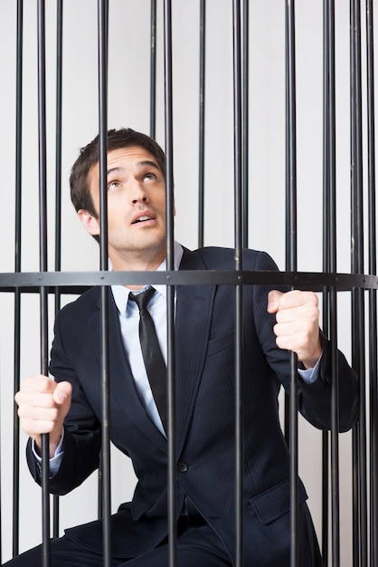 Фото Я не виноват! испуганный молодой человек в официальной одежде стоит за тюремной камерой и смотрит вверх