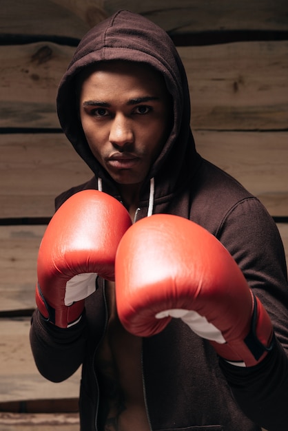 I am ready to fight. Confident young African man in hooded shirt and boxing gloves