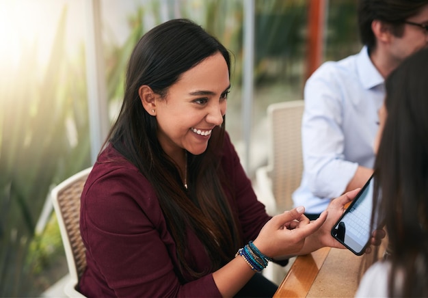 I am so relieved the years is done Shot of a cheerful young woman holding her cellphone while talking to another person at a table outside