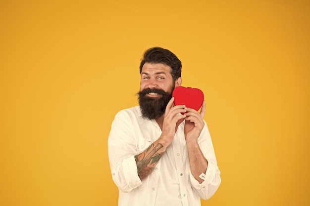 I believe in love preventing heart attack fall in love bearded man red heart brutal hipster yellow background happy valentines day heart poblems and disease having healthy habits in lifestyle