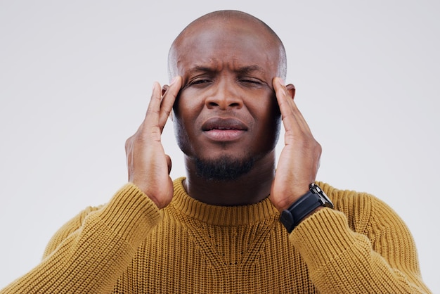 I can feel it starting again Shot of a young man holding his head while suffering from a headache against a grey background