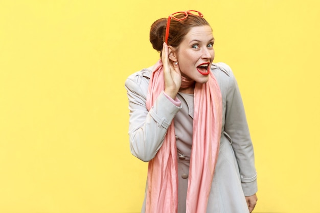 I can not hear you. Beautiful red head girl . Studio shot, yellow background. Studio shot