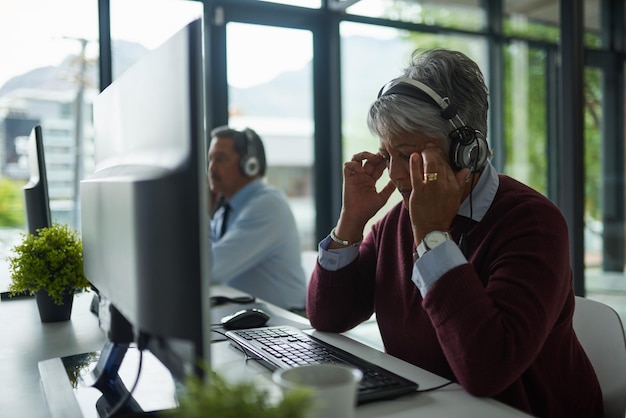 写真 コールセンターのコンピューターで作業しているときにストレスを感じている成熟した女性のこのショットのように焦点を合わせることができません