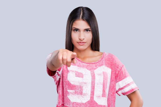 Foto io ti ho scelto! bella giovane cheerleader femminile che ti indica mentre sei in piedi su uno sfondo grigio