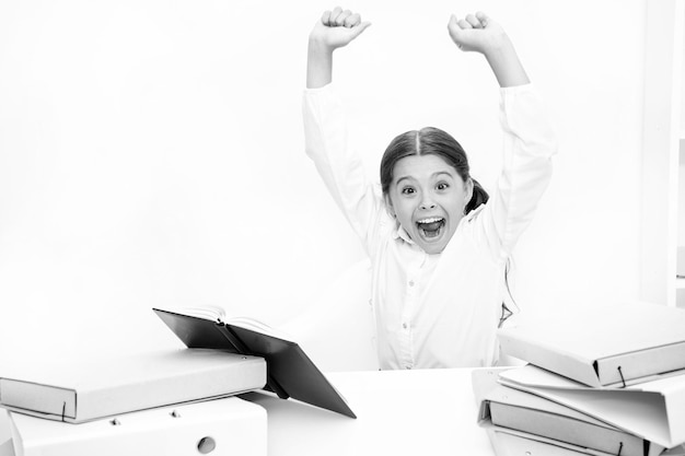 I did it Happy girl keeping her arms raised at desk Schoolgirl reading school book Small child have literature lesson Little girl reading lesson book in school Cute pupil develop reading skills