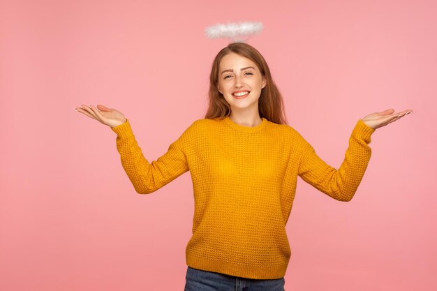 I don39t know Portrait of angelic ginger girl with halo over head shrugging shoulders in bewilderment looking at camera with question so what who cares studio shot isolated on pink background