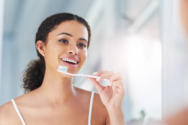 I dont talk dirty I talk fresh Cropped shot of an attractive young woman brushing her teeth in the bathroom at home