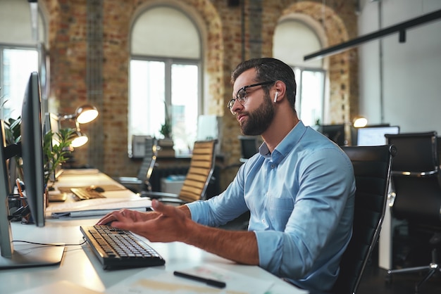 Photo i dont understand side view of young and successful bearded man in eyeglasses and headphones