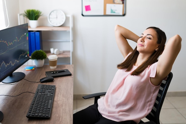 I feel so relaxed. Successful young woman closing her eyes and resting on her work chair after making a good business deal as a stock broker