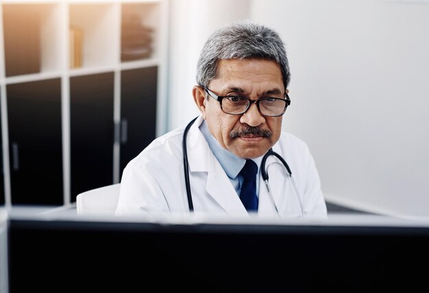 Photo i have my work cut out for me today cropped shot of a focused mature male doctor working on a computer while being seated in his office during the day