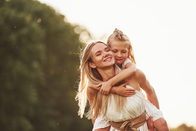 I hold you, don't worry. Mother and daughter enjoying weekend together by walking outdoors in the field. Beautiful nature.