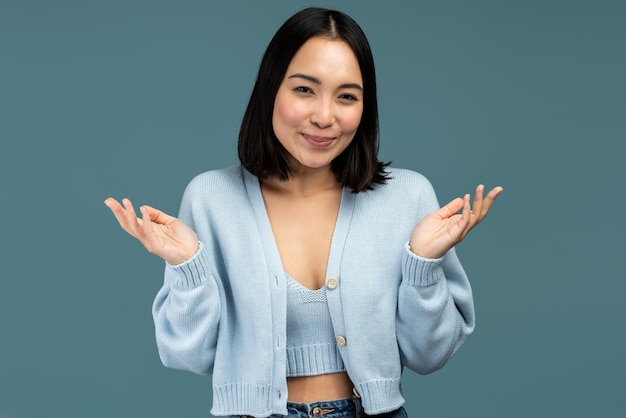 I don't know. portrait of confused beautiful brunette young
woman in casual style standing with raised arms and looking at
camera. indoor studio shot isolated on blue background