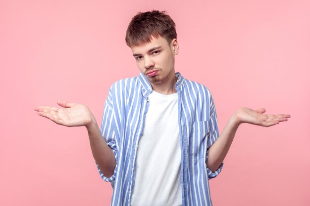 I don't know, sorry. Portrait of uncertain clueless brown-haired man with small beard and mustache raising hands, shrugging shoulders, no idea gesture. indoor studio shot isolated on pink background