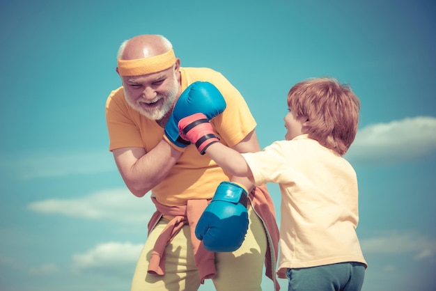 I love boxing Funny cute child fighting Grandpa and little child boy in boxing stance doing exercises with boxing gloves