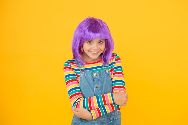 Фото Я люблю менять прически милая улыбка маленькой девочки с причудливыми волосами счастливый маленький ребенок носит парик с короткими волосами забавный ребенок с фиолетовыми синтетическими волосами красота и мода