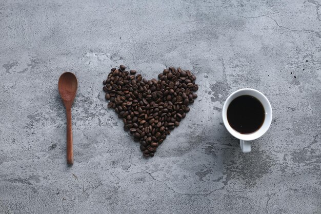 나는 회색 배경에 나무 숟가락, 커피 원두, 뜨거운 커피 한 잔으로 만든 커피를 좋아합니다.
