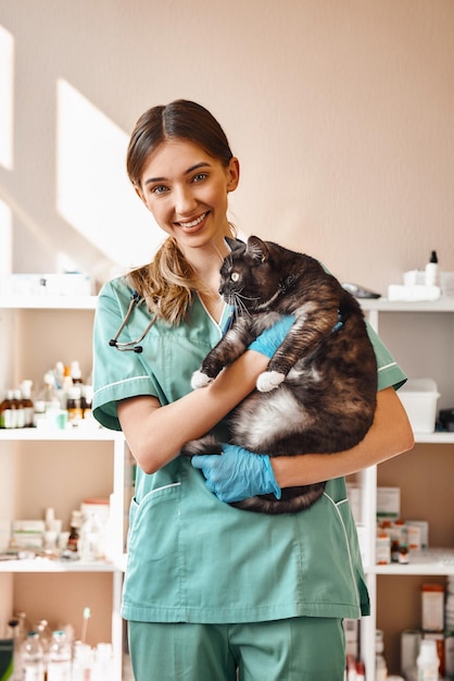 私は大きな黒いふわふわの猫を抱いている女性の獣医を笑っている私の患者のそれぞれが大好きです