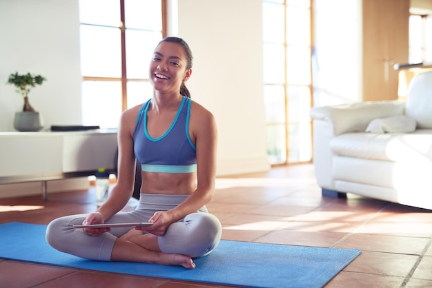 I love following workout videos online Portrait of a young woman using a digital tablet while exercising at home