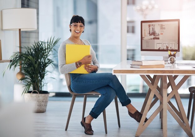 I love my job Full length portrait of an attractive young businesswoman sitting alone and holding files in her office