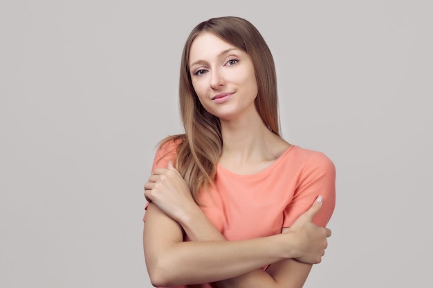 I love myself. Portrait of gentle lovely beautiful young woman with blonde straight hair hugging herself