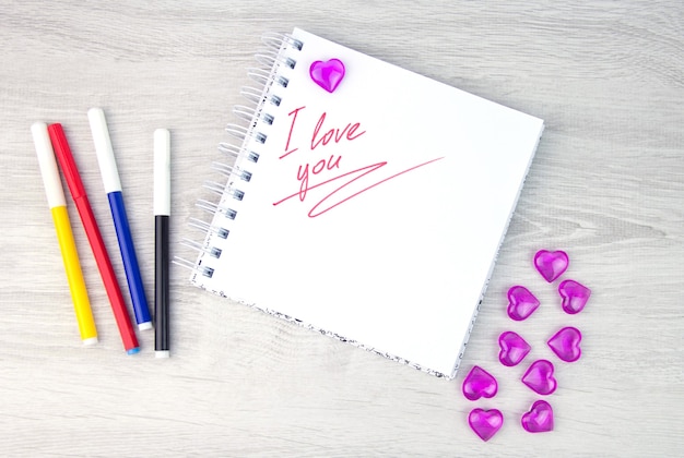 I love a pink letter, a valentine card, a notepad with the words i love you and a pen lying on a white background. valentine day. love letter. marker writing.