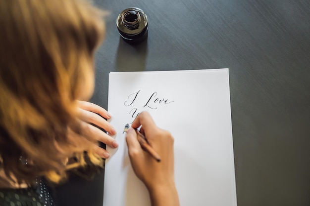 Photo i love you calligrapher young woman writes phrase on white paper inscribing ornamental decorated letters calligraphy graphic design lettering handwriting creation concept