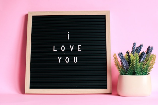 I LOVE YOU on letter board with decorative plant isolated on pink background