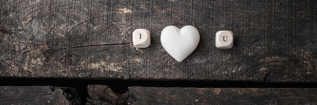 Photo i love you sign spelled on wooden dicer with marble made heart in the middle.